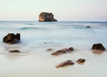 Cue es una playa de arena blanca y fina, con un entorno rocoso, que está unida por una barrera arenosa a una gran roca conocida como Isla Grande o Islona. Lugar idóneo para practicar buceo o para pescar. Se puede llegar a pie o en coche desde la localidad de Cué, una parroquia del concejo de Llanes, en el Principado de Asturias.