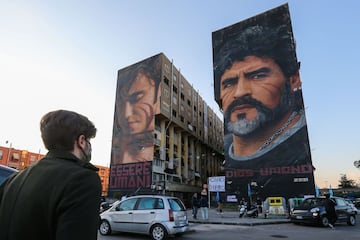 Peopple gather at the foot of a mural of late Argentinian football legend Diego Maradona (R) on November 26, 2020 in Naples, southern Italy, to mourn his death. - 