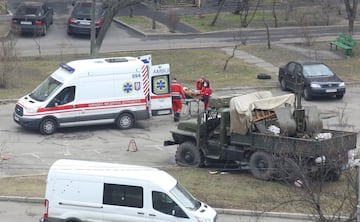 Emergency medical personnel load a person in military uniform onto an ambulance in a residential area of Kyiv.