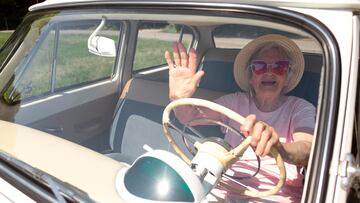Señora anciana conduciendo un coche con sombrero y gafas de sol