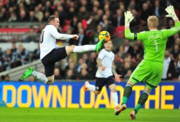 El delantero inglés Wayne Rooney salta para disparar al portero Kasper Schmeichel durante el partido de fútbol amistoso entre Inglaterra y Dinamarca en el estadio de Wembley en Londres