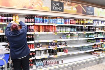 A supermarket worker stocks soft drinks in London, Britain, 22 July 2021. British supermarkets are struggling to stock shelves due to staff going into self isolation after being pinged by the NHS app.