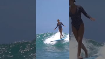 A woman walks from end to end on her board, moves slowly, and uses her arms to keep her balance which makes her look like she were walking on the wave.