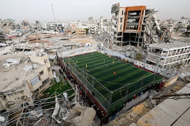 Dos equipos palestinos disputan un partido de fútbol ante numerosos espectadores en una cancha en la ciudad de Gaza. La imagen del recinto deportivo junto a las ruinas y los escombros de varios edificios, destruidos por las bombas durante más de dos años de ofensiva israelí, resulta impactante a la vez que sobrecogedora.
