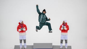 Brazil's gold medalist Lucas Pinheiro Braathen (C) leaps onto the podium flanked by Switzerland's silver medalist Marco Odermatt (L), and Switzerland's bronze medalist Loic Meillard during the podium of the men's giant slalom alpine skiing event during the Milano Cortina 2026 Winter Olympic Games at the Stelvio Ski Centre in Bormio (Valtellina) on February 14, 2026. (Photo by Fabrice COFFRINI / AFP)