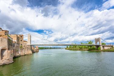 La construcción del puente comenzó en 1915 y fue finalizada en 1921. Fue diseñado por el ingeniero José Eugenio Ribera. Inspirado en el famoso Puente de Brooklyn de Nueva York, fue el segundo puente colgante del mundo construido con un sistema de hormigón armado, lo que lo convirtió en una obra pionera de su época. El puente fue destruido durante la Guerra Civil Española debido a su importancia estratégica y fue reconstruido manteniendo su diseño y características originales, reabriéndose al público en 1939.