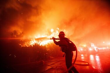 Un bombero lucha contra el incendio de Palisades mientras arde durante una tormenta de viento en el lado oeste de Los Ángeles.