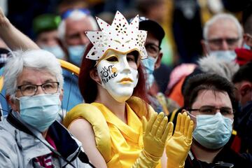 Una aficionada ataviada con un disfraz, y con el rostro cubierto por una máscara de Carnaval con el logo del Tour de Francia, destaca en medio de un grupo de seguidores con mascarillas quirúrgicas. La curiosa imagen fue captada durante la cuarta etapa de la carrera francesa, entre las localidades de Redon y Fougères. 