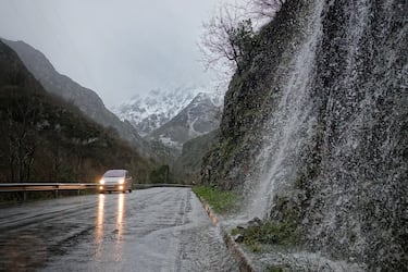 Un coche circula por una carretera mojada a causa de la nieve en Ponga, Asturias. La Agencia Estatal de Meteorología (Aemet) ha elevado a naranja el nivel de alarma en Asturias, tanto por fenómenos costeros, como por acumulaciones de nieve que podrían ser de 20 centímetros en cotas superiores a los 1.000 metros. No solo los puntos más altos de la región se teñirán de nieve. La Aemet avisa de que hoy nevará por encima de los 300 metros en el interior y que en estos puntos podrían registrarse acumulaciones de hasta cinco centímetros de nieve.
