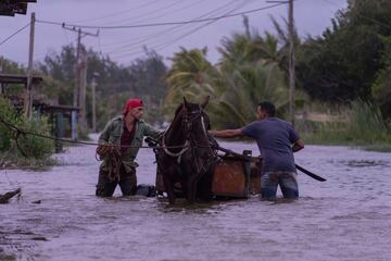 Unos hombres recorren una calle inundada con un carruaje tirado por caballos tras el paso del huracán Helene en Guanimar, provincia de Artemisa, Cuba.