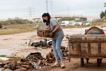 Una mujer lleva una mascarilla en una calle cubierta de barro, tras las fuertes lluvias que provocaron inundaciones en Valencia.