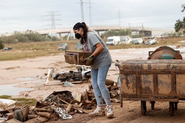 Una mujer lleva una mascarilla en una calle cubierta de barro, tras las fuertes lluvias que provocaron inundaciones en Valencia.
