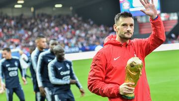 (FILES) In this file photo taken on October 10, 2018 French goalkeeper Hugo Lloris presents the World Cup trophy flanked by teammates after a training session on October 10, 2018 in Guingamp, western France, on the eve of the friendly football match France vs Iceland. - French goalkeeper Hugo Lloris, captain of the 2018 world champions and the most capped player in the history of the French football team (145 caps), announced his international retirement in an interview with sports daily L'Equipe, on January 9, 2022. (Photo by LOIC VENANCE / AFP)