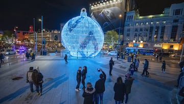 MADRID, SPAIN - NOVEMBER 26: People watch a Christmas lights installation shaped as a massive ball at Alcala Street on November 26, 2020 in Madrid, Spain. The Madrid council has increased their budget for the traditional Christmas lights to 3.17 million euros this year, amid measures to control the coronavirus pandemic. The council has also included lights in the design of the Spanish flag measuring up to one kilometer as a new feature in this year's installation. (Photo by Pablo Blazquez Dominguez/Getty Images)