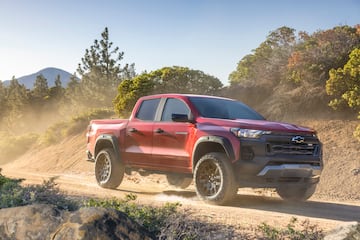 Front 3/4 view of Colorado Trail Boss driving down a dirt road during golden hour.