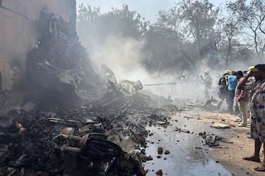 Personas se encuentran entre los escombros en el lugar donde se estrelló un avión en la ciudad de Ahmedabad.