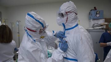 Imagen de dos profesionales sanitarios preparándose para atender a pacientes de coronavirus después de equiparse con los equipos de protección individual (EPI).