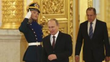 Vladimir Putin (C) seguido por Sergei Lavrov, ministro ruso de Asuntos Exterrores, a su llegada a la ceremonia de presentación de credenciales de los nuevos embajadores en Moscú.