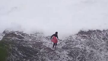 Un surfista que intentaba entrar al agua por unas rocas, huye de una gran ola que se acerca a su posici&oacute;n en S&iacute;dney (Australia).