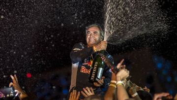 Carlos Sainz descorcha el champán en el podio del Dakar 2018.