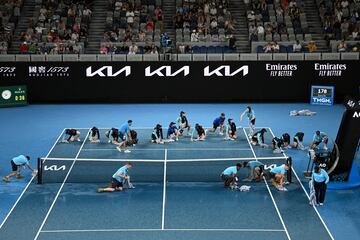 La lluvia hizo acto de presencia ayer en Melbourne durante el Abierto de Australia de tenis. Así lo refleja esta curiosa imagen, en la que los asistentes del torneo se afanan en secar el agua de la pista con toallas durante el partido de primera ronda entre el australiano Álex de Miñaur y Yu Hsiou Hsu, de Hong Kong, en Melbourne Park.