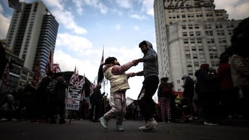 -FOTODELDÍA- AME6533. BUENOS AIRES (ARGENTINA), 18/06/2021.- Dos niños bailan en una calle mientras miles de personas se manifiestan reclamando ayudas del Gobierno para atravesar la crisis económica generada por la COVID-19, hoy en Buenos Aires (Argentina). EFE/ Juan Ignacio Roncoroni