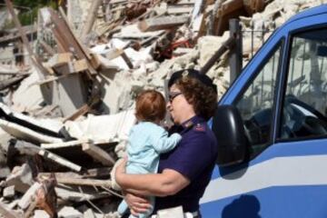 ITA45 PESCARA DEL TRONTO (ITALIA) 24/08/2016.- Una agente de policía lleva en brazos a un bebé cerca de los escombros de varios edificios en Pescara del Tronto, cerca de la localidad de Arquata del Tronto, en la provincia de Ascoli Piceno, región de Marche, en el centro de Italia, hoy, 24 de agosto de 2016. Al menos 19 personas han fallecido y hay decenas de heridos tras el terremoto de 6 grados en la escala Richter que ha sacudido el centro de Italia esta madrugada, según informó la televisión pública RAI. EFE/Crocchioni