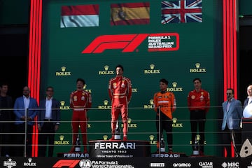 Imagen completa del podio con Carlos Sainz en el escalón central como vencedor de la carrera, a su derecha, su compañero en Ferrari el monegasco Charles Leclerc, y a la izquierda de Sainz, el piloto británico de McLaren Lando Norris que terminó tercero en Australia.