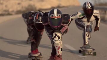 Tres chicas de las Longboard Girls Crew equipadas con mono y casco, patinando en longboard por una carretera de Israel en 2013, para la pel&iacute;cula Open de LGC. 