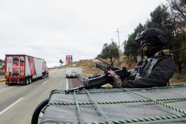 Un miembro de la Guardia Nacional se encuentra a bordo de un vehículo en el lugar de la carretera que conecta la Ciudad de México con el estado de Puebla, donde desconocidos incendiaron un autobús y un tráiler, tras bloqueos y ataques incendiarios perpetrados por miembros del crimen organizado.