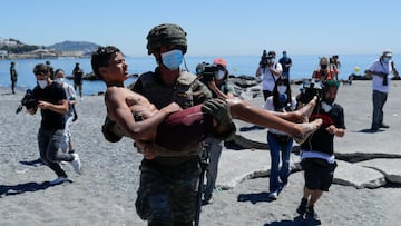 A Spanish soldier carries a migrant near the fence between the Spanish-Moroccan border, after thousands of migrants swam across the border, in Ceuta, Spain, May 19, 2021. REUTERS/Jon Nazca