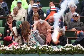 Un manifestante corre a la cancha con una bengala encendida durante el partido de la final individual masculina entre Rafael Nadal y David Ferrer en Roland Garros