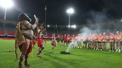 El cantante Luther Cora y el grupo Yugambeh Dancers realizan la ceremonia ind&iacute;gena del humo en presencia de los jugadores del Gold Coast Suns antes de su partido de f&uacute;tbol australiano disputado ayer en el Metricon Stadium contra los Hawtorn 