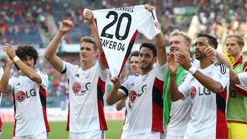 Lars Bender y Hakan Calhanoglu sostienen la camiseta de Charles Aranguiz, en una muestra de apoyo para el jugador que sufri&oacute; una grave lesi&oacute;n.