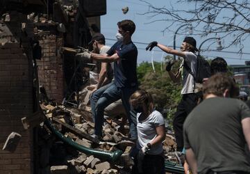 MINNEAPOLIS, MN - MAY 30: People work to clean up outside a burned building on May 30, 2020 in Minneapolis, Minnesota. Buildings and businesses around the Twin Cities have been looted and destroyed in the fallout after the death of George Floyd while in police custody. Police Officer Derek Chauvin has been charged with third-degree murder and manslaughter in Floyd's death. Stephen Maturen/Getty Images/AFP == FOR NEWSPAPERS, INTERNET, TELCOS & TELEVISION USE ONLY ==