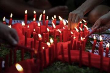 Varios asistentes encienden vela alrededor de un lazo rojo simb¨®lico para celebrar el D¨ªa Mundial de lucha contra el Sida en Quezon (Filipinas).