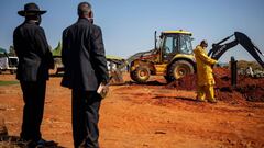 A relative and a pastor overlook as undertakers wearing personal protective equipment (PPE) bury the casket containing the remains of Steward Motlhabane, who died of COVID-19 coronavirus, during the funeral at the Westpark cemetery in Johannesburg, on Jul