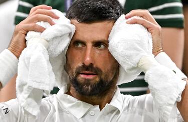 El serbio Novak Djokovic usa su toalla para refrescarse durante un descanso mientras juega contra el francés Alexandre Muller durante su partido de tenis de primera ronda individual masculino en el segundo día del Campeonato de Wimbledon 2025.