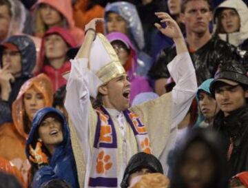 Un seguidor vestido de Papa entretiene al resto de aficionados durante un partido de fútbol.