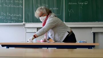 Un maestro limpia y desinfecta sillas y mesas en la escuela secundaria Phoenix Gymnasium en Dortmund, Alemania; 2020.