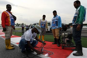 Los operarios del circuito de Sepang arreglan la alcantarilla que provocó el accidente del piloto francés.