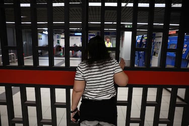 Una mujer espera cerca de una puerta en una estación de metro mientras las operaciones se reanudan parcialmente.