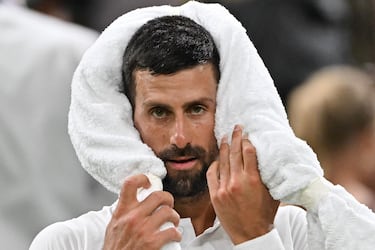 El serbio Novak Djokovic usa su toalla para refrescarse durante un descanso mientras juega contra el francés Alexandre Muller durante su partido de tenis de primera ronda individual masculino en el segundo día del Campeonato de Wimbledon 2025.