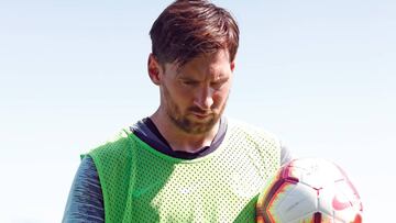 Lionel Messi durante un entrenamiento caminando cabizbajo y con un bal&oacute;n en la mano. 