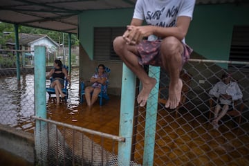 La gente descansa en un porche inundado tras el paso del huracán Helene en Guanimar, provincia de Artemisa, Cuba.