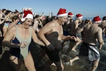 Decenas de ciudadanos participaron este mediodía en el tradicional primer baño del año en la playa de Sant Sebastià del barcelonés barrio de la Barceloneta.