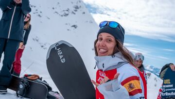Núria Castán haciendo el shaka con la mano y sonriendo, con su tabla de snowboard, en el YETI Xtreme Verbier 2024.