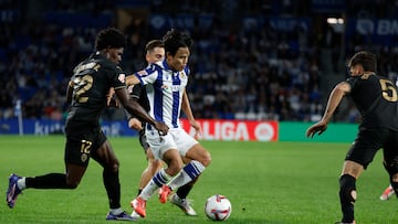 SAN SEBASTIÁN, 28/09/2024.- El delantero de la Real Sociedad Take Kubo (c) juega un balón entre Thierry Correia (i) y Enzo Barrenechea (d), ambos del Valencia, durante el partido de LaLiga en Primera División que Real Sociedad y Valencia CF disputan este sábado en el Reale Arena, en San Sebastián. EFE/Javier Etxezarreta