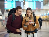 Happy couple, airport and phone with ticket, travel app and adventure with excited face, conversation and smile. Man, woman and smartphone for digital booking of hotel, taxi or bus for transportation PAREJAS AEROPUERTO
