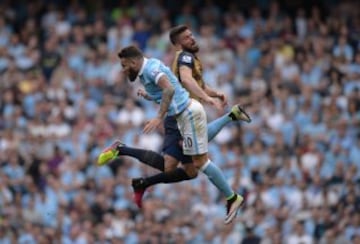 El jugador francés del Arsenal, Giroud, y el defensa argentino del Manchester City, Otamendi, parecen llevar caminos distintos en un salto, aunque parece que ninguno se lleva el balón.